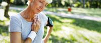 older woman with hand on heart in a park
